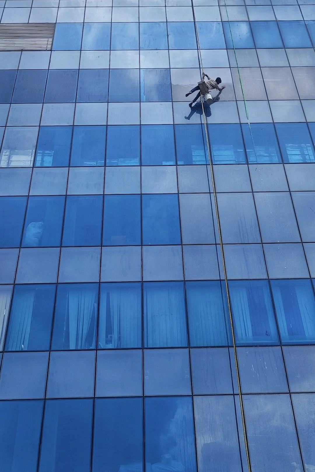 High-rise window washers in safety gear cleaning a skyscraper facade.